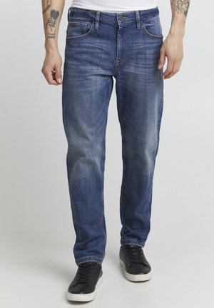 Denim jeans in blue with a faded design, straight cut, five pockets, and contrasting stitching. Paired with black sneakers.