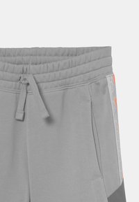 Grau Sportshorts mit elastischem Bund und Kordelzug. Verfügt über Seitentaschen und orangefarbene Akzente am Saum und den Nähten.