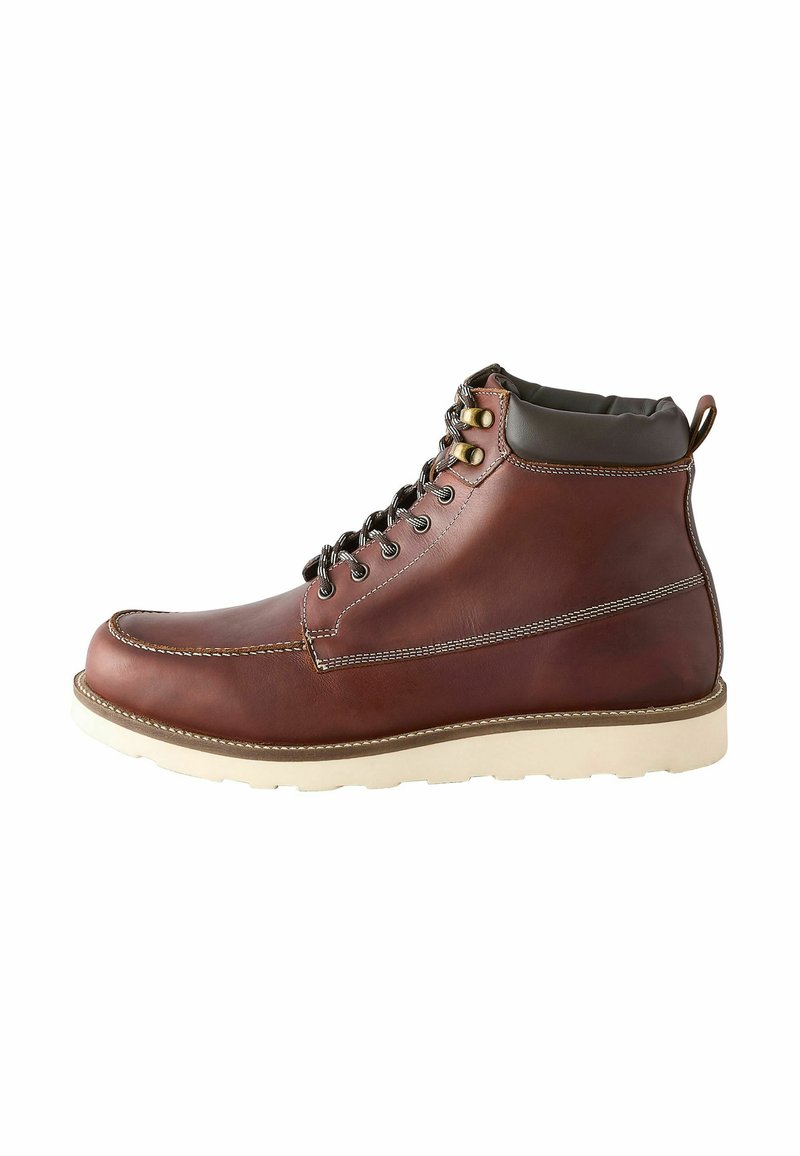 Boot din piele maro cu o finisare netedă, talpă din cauciuc alb și guler căptușit de culoare maro închis. Include ochiuri metalice șiCusături contrastante.