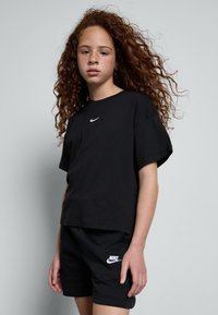 Svart bomull t-skjorte med kort erme, med en liten hvit Nike-logo på brystet. Kombinert med svarte shorts med en hvit logo.