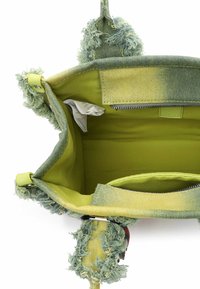 Zielona i żółta torebka z miękką, teksturowaną powierzchnią, puszystymi akcentami oraz podszytym wnętrzem z kieszenią na zamek i metką.