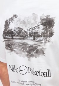 Εξωτερικό γήπεδο μπάσκετ με δύο καλάθια, περιβαλλόμενο από δέντρα και κτίρια, τυπωμένο σε ασπρόμαυρο σε λευκό ύφασμα.