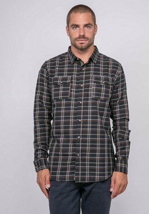 Chemise à carreaux noire et bleu foncé à manches longues, boutonnée à l'avant, avec deux poches poitrine et des lignes contrastantes beiges et marron.