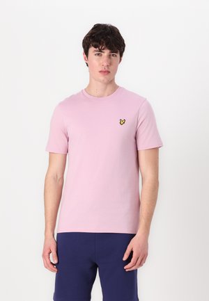 Rosa bomulls-T-shirt med rundad halsringning och korta ärmar. Har en liten gul fjärilslogotyp på vänster bröst. Bärs med marinblå shorts.