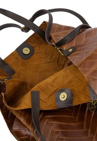 Bruine leren tas met een geweven textuur, met een interieur van suède in een lichtere bruin. Inclusief bruine handvatten en accenten van messing hardware.