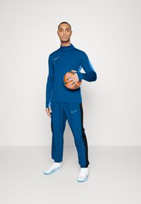 Nike Performance NIKE ACADEMY23 TRACK PANTS - Donji dijelovi trenirke - green abyss/black/baltic blue