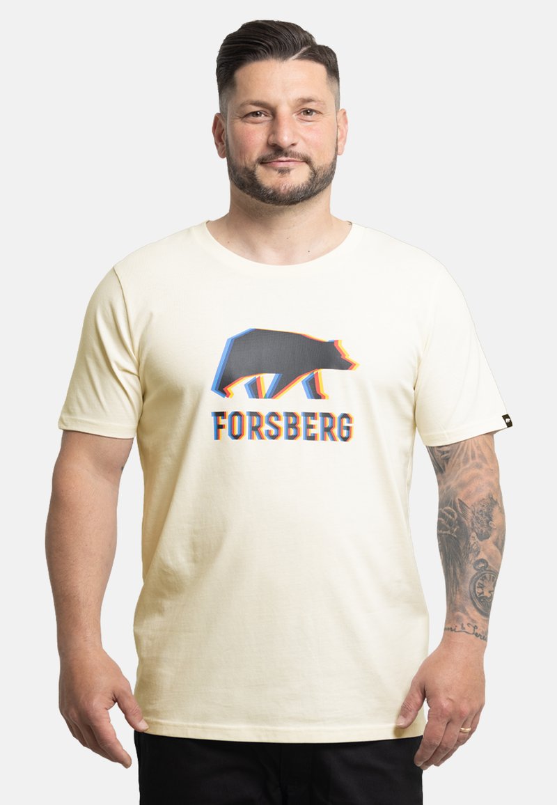 Mężczyzna o krótkich ciemnych włosach i brodzie, ubrany w jasny t-shirt z stylizowanym niedźwiedziem i napisem „FORSBERG”, pokazujący wytatuowane prawe przedramię.