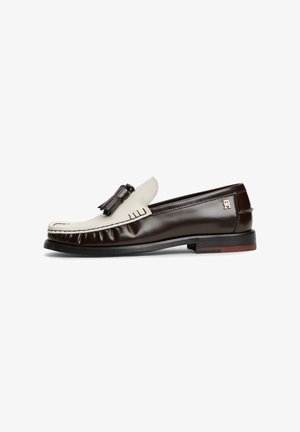 Zweifarbiger braun-cremefarbener Lederloafer mit Quasten-Detail und kleinem Logo an der Ferse, von der Seite auf weißem Hintergrund gezeigt.
