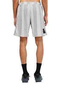 Grå shorts med ett geometriskt mönster, elastiskt midjeband, sidoflikar och en liten svart logotypaccents. Kombinerade med svarta strumpor och grå skor.