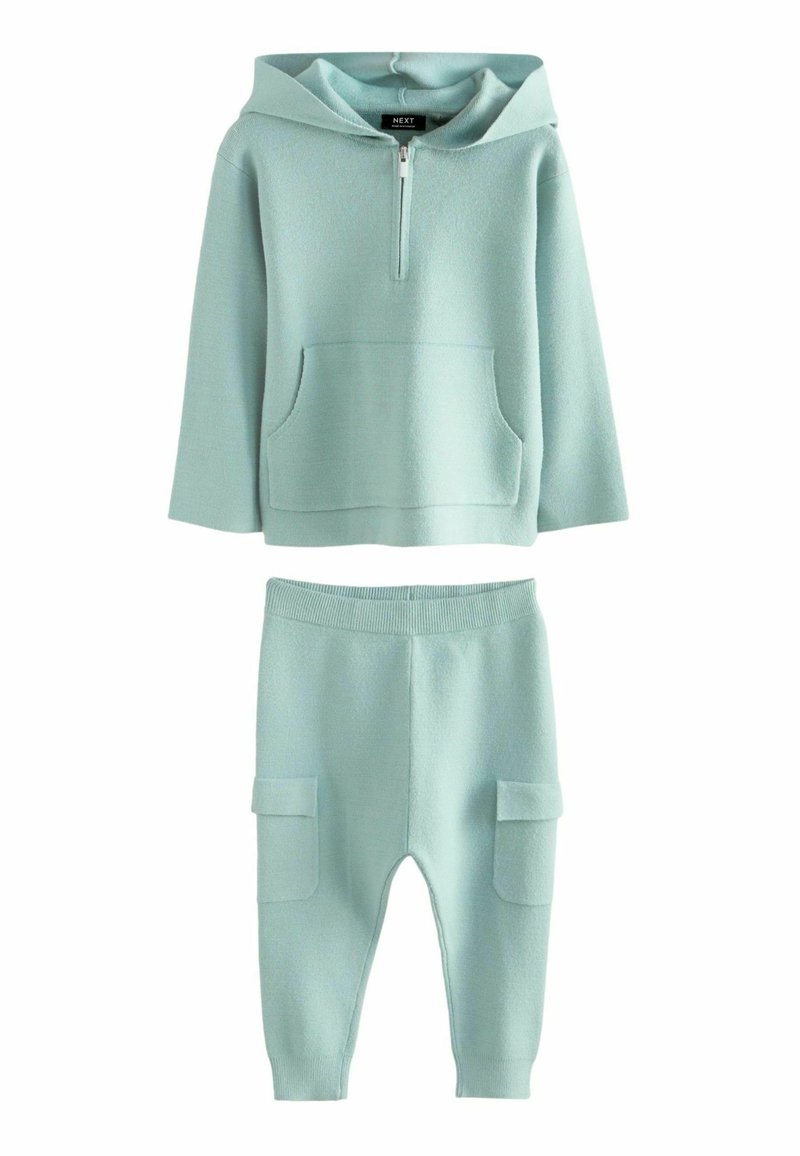 Ljus mintgrön hoodie med halvdragkedja och framficka, kombinerad med matchande byxor med cargofickor på sidorna.