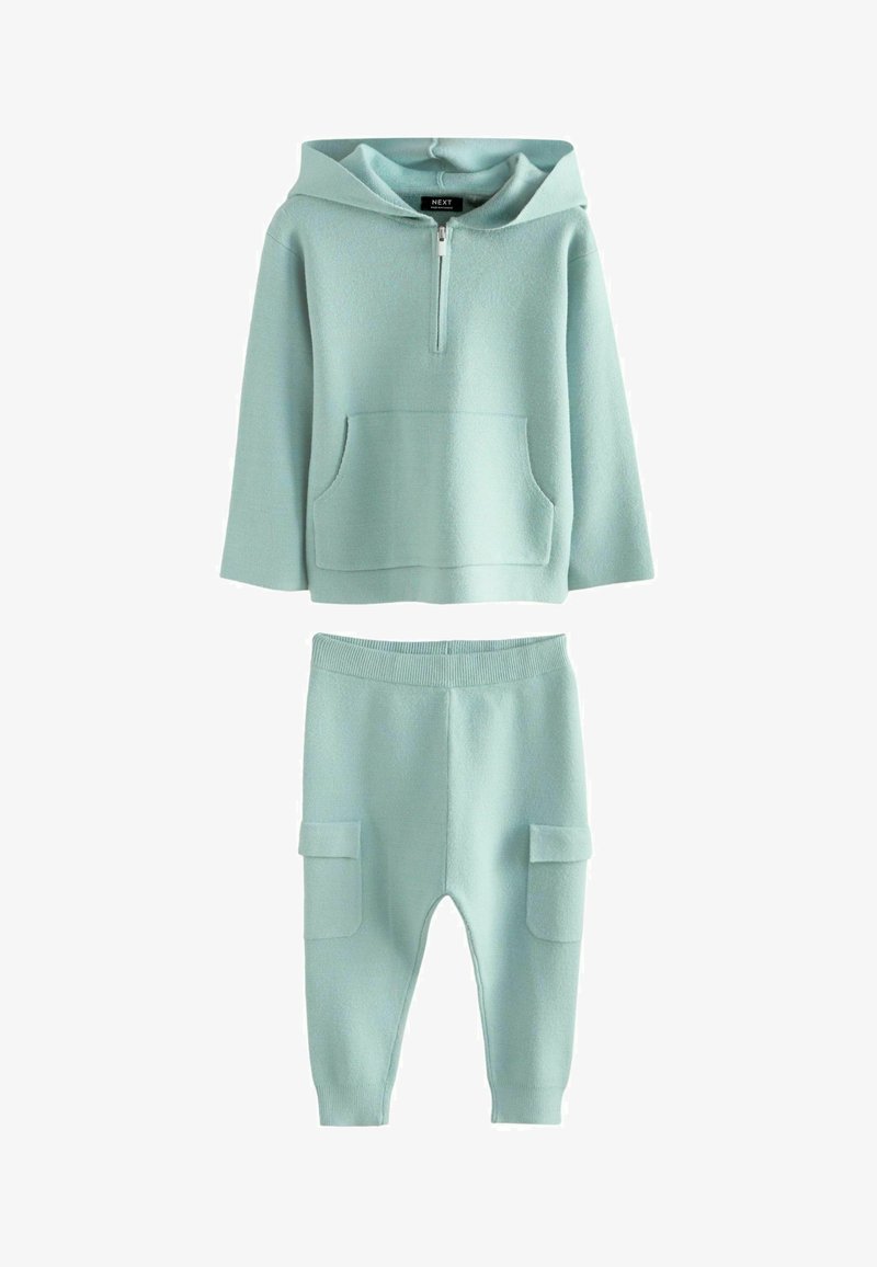 Ljus mintgrön hoodie med halvdragkedja och framficka, kombinerad med matchande byxor med cargofickor på sidorna.