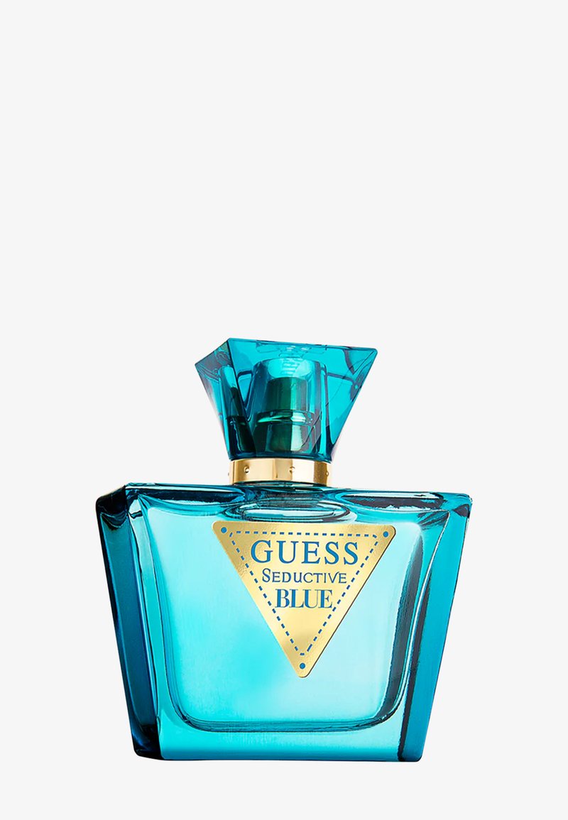 Türkisfarbenes Glas-Parfümfläschchen mit einem geometrischen Verschluss, einem goldenen Halsring und einem goldenen, dreieckigen Etikett mit der Aufschrift "Guess Seductive Blue".