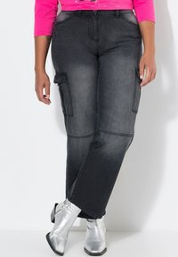 Pantaloni cargo grigi scuri con tasche laterali e una vestibilità comoda, abbinati a stivaletti alla caviglia argentati e lucidi. Texture in denim morbido.
