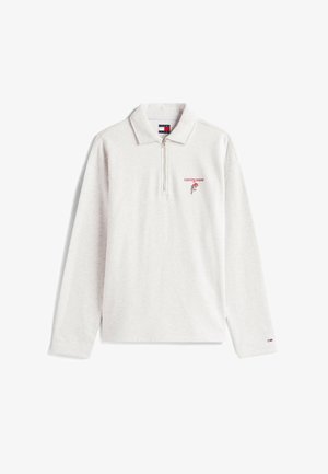 Jasnoszara polo z długim rękawem z kołnierzykiem na zamek błyskawiczny, z czerwonym haftem i wzorem róży po lewej stronie klatki piersiowej. Materiał bawełniany.