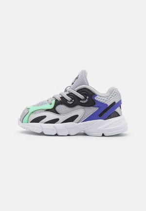 Baskets Adidas grises avec des touches noires, vertes et bleues, tissu en mesh, design à lacets et semelle blanche épaisse, vues du côté gauche.