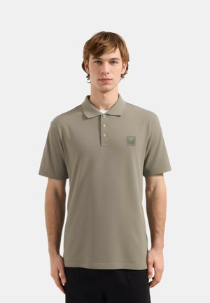 Olive zelena polo majica s klasičnim ovratnikom, tri dugmeta, kratkim rukavima i malim vezom logotipa na grudima.