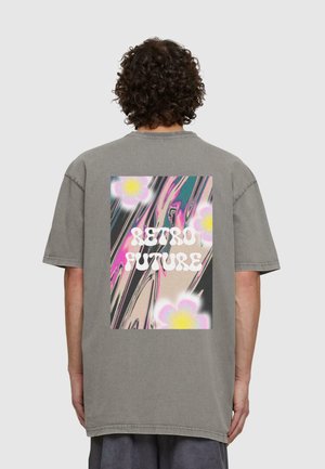 Grå oversized t-skjorte med grafikk på baksiden som viser snurrende mønstre i rosa og beige, samt teksten "RETRO FUTURE" i fet hvit skrift.