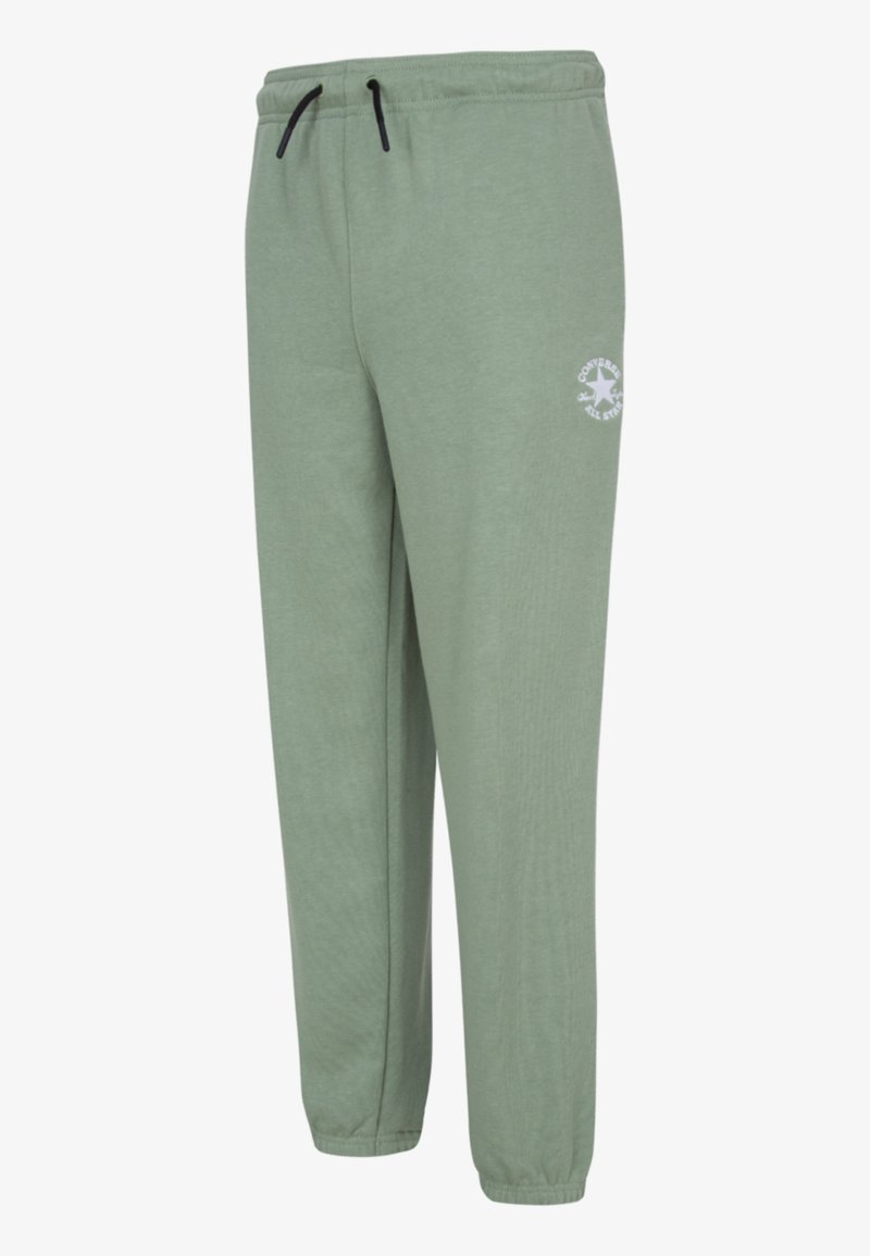 Grønne joggebukser laget av mykt stoff, med snøring i livet, smale ben og en hvit logo på venstre lår.