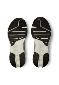 Scarpe sportive con suole nere in gomma caratterizzate da un evidente disegno del battistrada, intersuola bianca e accenti azzurri chiari sui lati.