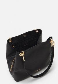 Black textured leather handbag with golden hardware, featuring a zip pocket inside and a front snap closure. Single shoulder strap included.