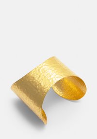 Zlatni manžetni izraz sa udarjenim efektom i glatkim, zakrivljenim oblikom. Reflektirajući površina pojačava svjetlost, ističući njegovu metalnu teksturu i oblik.