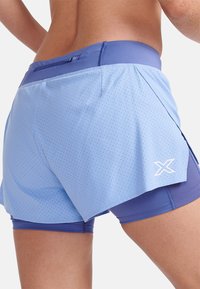 Ljust blå löparshorts med ett perforerat mönster, utrustade med ett enhetligt blått innerskikt och en sidospalt för rörelsefrihet. Vit logotypaccent.