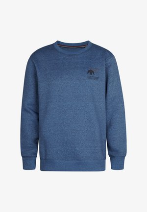 Niebieski polarowy sweter o okrągłym dekolcie, z małym nadrukowanym logo na piersi, zestawiony z ciemnoniebieskimi dżinsami i czarnymi butami.