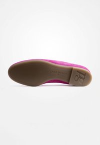 Roze suède schoen met een bruine rubberen zool. Kenmerkt zich door een ronde teen en een gladde textuur. Logo gedrukt op de zool.