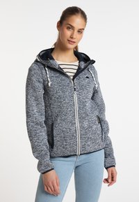 Giacca con cappuccio e zip in un tessuto a maglia blu e grigio testurizzato. Presenta dettagli in blu navy, lacci e tasche laterali. Camicia a righe sotto.