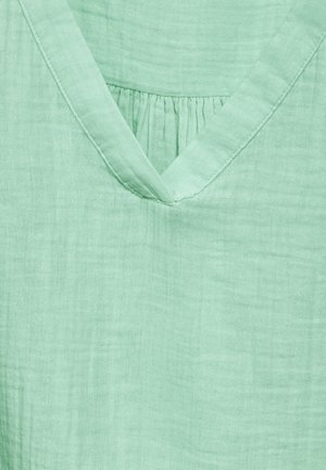 Miętowa bluzka wykonana z lekkiego materiału, z dekoltem w serek i subtelnymi marszczeniami, o miękkiej, teksturowanej powierzchni.
