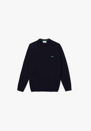 Pull en maille bleu marine avec un col rond, des poignets et un ourlet côtelés, présentant un petit accent logo vert sur la poitrine et une finition texturée.
