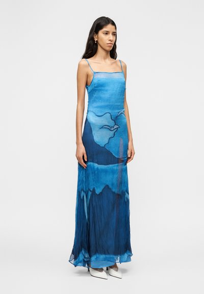 Μακρύ φόρεμα χωρίς μανίκια από ύφασμα με μπλε διαβάθμιση που απεικονίζει ένα σχέδιο βουνών και πουλιών σε υδατογραφία, με αέρινη και ελαφριά υφή.