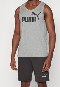 Grijs katoenen tanktop met zwart "PUMA" logo en silhouet. Gecombineerd met zwarte shorts met een klein wit logo op de linker bovenbeen.