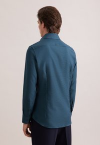 Blauwgroen shirt met lange mouwen, een gestructureerd patroon, knoopmanchetten en een klassieke kraag. Getailleerde pasvorm met een gebogen zoom.