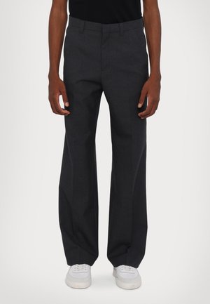 Tumši pelēki pielāgoti bikses ar taisnu piegriezumu, izgatavotas no gludas auduma, ar jostas cilpām un sānu kabatām, apvienotas ar baltām sporta kurpēm.