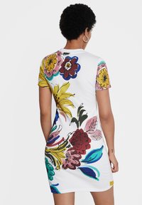 Robe à manches courtes blanche avec un imprimé floral multicolore comprenant des accents jaunes, roses, rouges et bleus ; texture côtelée.