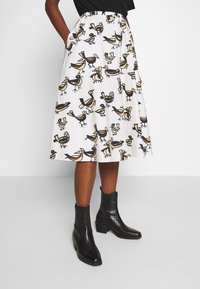 Witte midi-rok met een speels vogelpatroon in zwart en beige. Elastische tailleband, zijzakken en een vloeiend ontwerp.