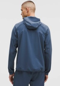 Waterdichte marineblauwe jas met capuchon, gladde textuur, verstelbare manchetten en een minimalistisch ontwerp, met subtiele naaddetails.