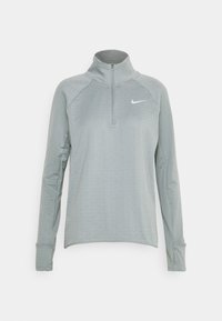 Ljusgrå långärmad sporttröja med halv dragkedja fram, ståkrage, tumhål i ärmslut och en liten vit Nike-logotyp på bröstet.