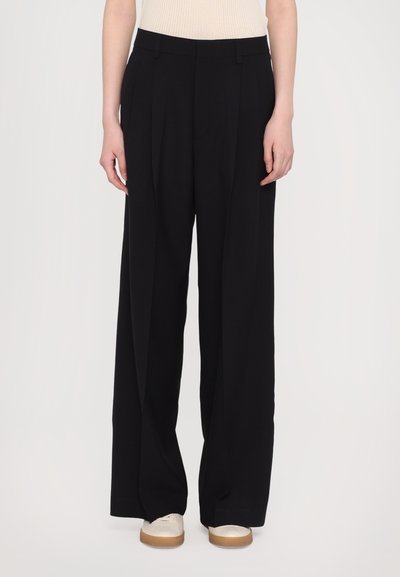 Pantalons noirs à jambes larges en tissu lisse, présentant une taille haute, des plis avant et des poches latérales, avec une apparence nette et soignée.