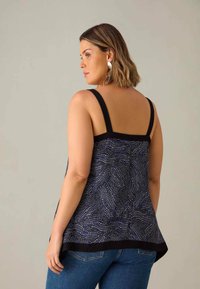 Mörkblå ärmlös topp med ett texturerat mönster av vågiga linjer, svart kantsöm och justerbara band. Kombineras med denimjeans.