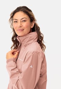 Light pink waterproof jacket with high collar, zipper closure, and subtle texture. Features logo on chest and sleeve. Smooth material.