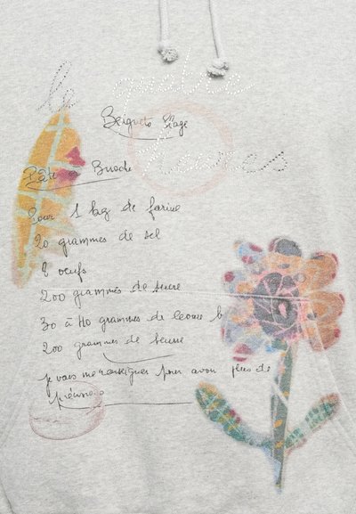 Šedá mikina s farebnými kvetinovými vzormi a ručne písaným textom receptu. Text je v čiernej a hnedej farbe, pričom niektoré prvky sú zvýraznené farbou.