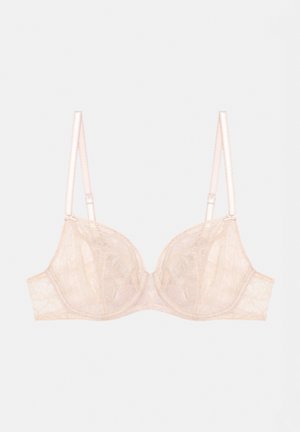 Soutien-gorge en dentelle nude, avec des bonnets à armatures, des bretelles réglables et un motif floral. Texture douce avec des détails à bords festonnés.