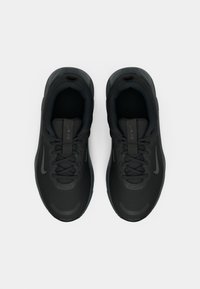 O pereche de pantofi de alergare Nike negri cu șireturi, văzuți dintr-o perspectivă de sus pe un fundal alb.