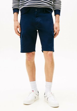 Pantalones cortos cargueros en color navy con bolsillos laterales, diseño ajustado y textura suave, combinados con zapatillas blancas y calcetines de caña baja.