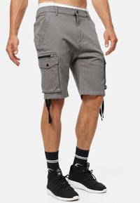 Shorts cargo gris avec poches latérales, fermeture éclair, passants de ceinture et cordons réglables à l'ourlet. Fabriqués en tissu léger mélangé coton.