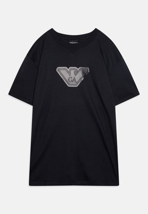 Crna pamučna majica opuštenog kroja, s velikim srebrnosivim logotipom na prednjem dijelu. Kratki rukavi i okrugli izrez.