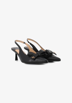 Tacones negros tipo slingback en piel texturizada con punta afilada y un gran lazo decorativo. Presentan un pequeño acento dorado en el lazo y un tacón de altura media.