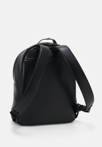 Schwarzer Leder-Rucksack mit glatter Textur, verstellbaren Trägern und einem minimalistischen Design ohne sichtbare Hardware oder Muster.